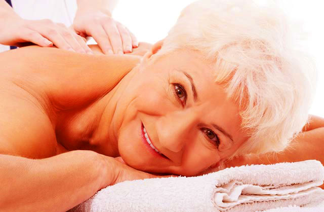 Older woman with all white head of hair  enjoying a massage lying down on massage table
