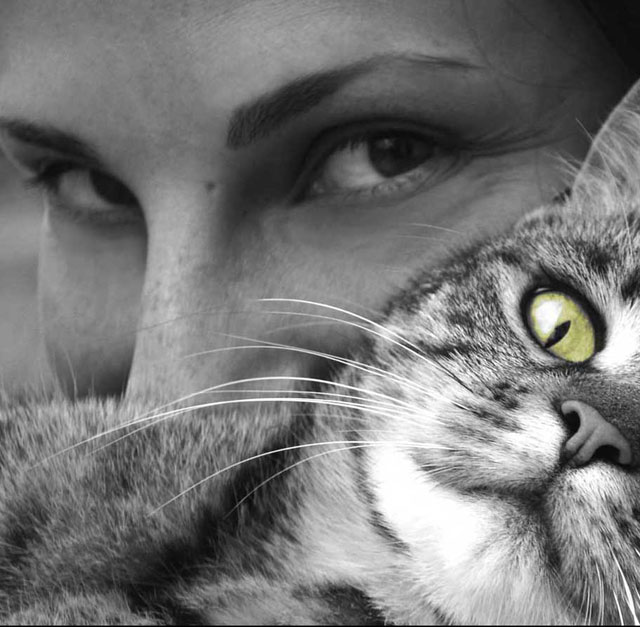Woman with cat in blace and white image except for cats green eyes