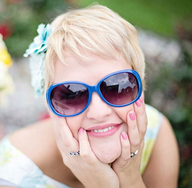 Gorgeous woman with flower in her hair and blue sunglasses